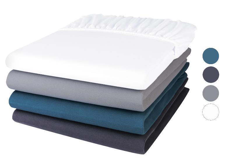 Stapel hoeslakens: wit, grijs, teal en donkergrijs.