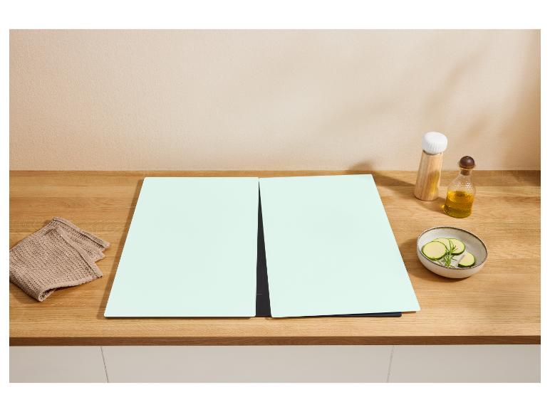 Twee mintgroene snijplanken op een houten aanrecht met een handdoek, olie en gesneden courgette.
