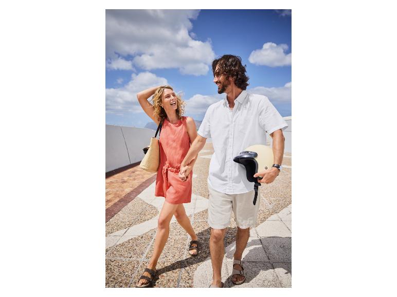 Koppel in zomerse kleding loopt, motorhelm in de hand.