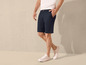 Man draagt blauwe chino shorts en witte sneakers.