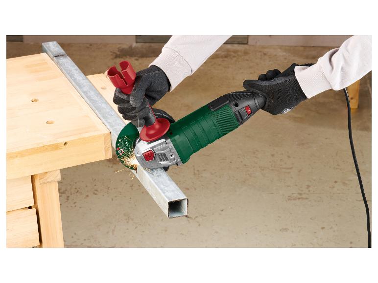 Persoon snijdt metaal met een haakse slijper, vonken vliegen, op een houten werkbank.