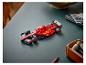 Een rode Lego Ferrari Formule 1-auto op een donkergroen bureau met kantoorartikelen.