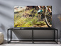 Een flatscreen-tv op een zwarte tv-tafel, met een beeld van een mountainbiker.