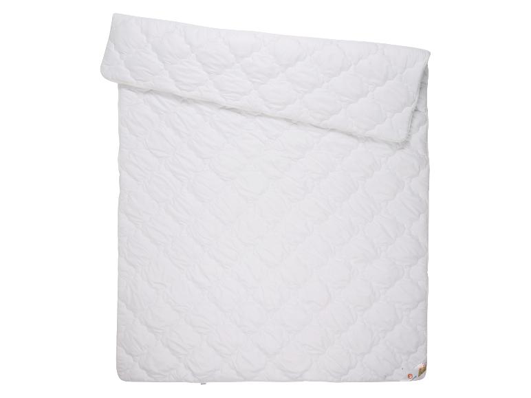 Wit gewatteerd dekbed, opgevouwen en uitgespreid op een witte achtergrond