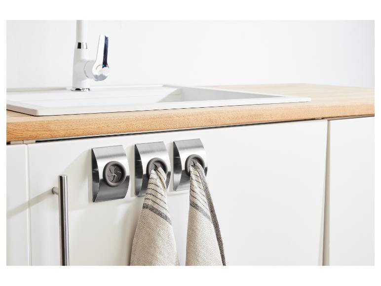 Keuken met spoelbak, kraan en drie roestvrijstalen handdoekhouders met theedoeken.