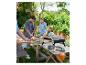 Familie maakt pizza's buiten met draagbare oven en pizza-gereedschap.