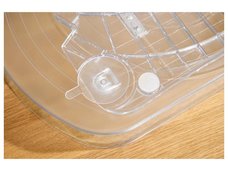 Transparante plastic bak met rasterpatroon en ronde bevestigingen op een houten ondergrond.