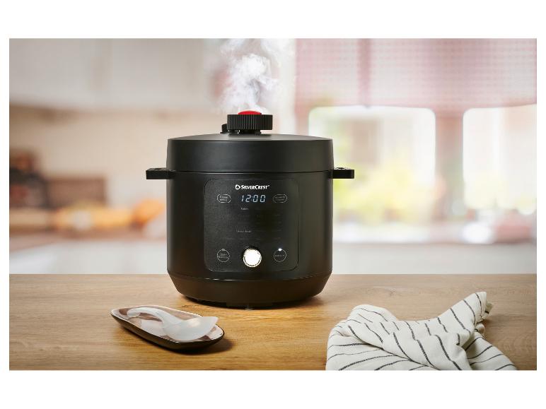 Zwarte elektrische snelkookpan met digitaal display '12:00' en ontsnappende stoom.