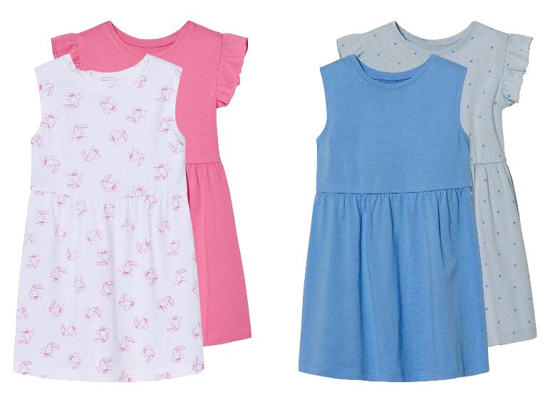 Twee meisjesjurkjes: één met een toucaanprint en één effen blauwe.