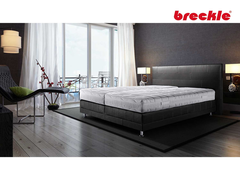 Een zwart lederen boxspringbed met een witte matras van Breckle.
