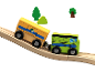 Houten speelgoedtrein met twee wagons op een oplopende baan, met bomen op de achtergrond.