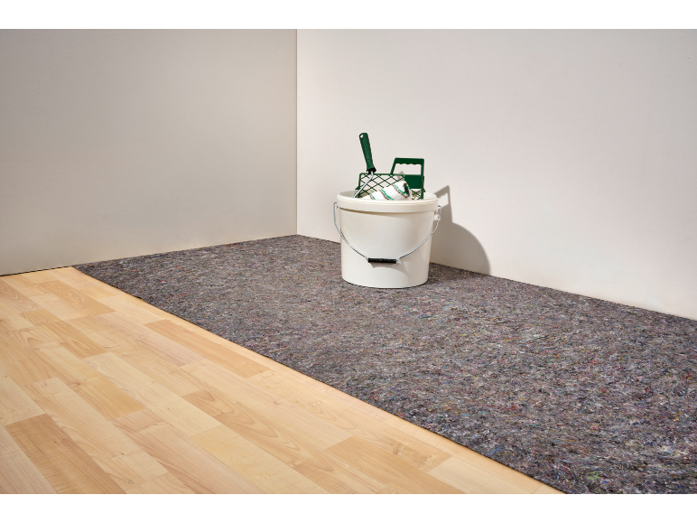 Verf gereedschap in een emmer op vloerbedekking.