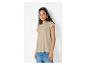 Vrouw in beige T-shirt en jeans, met zilveren oorbellen en armband.