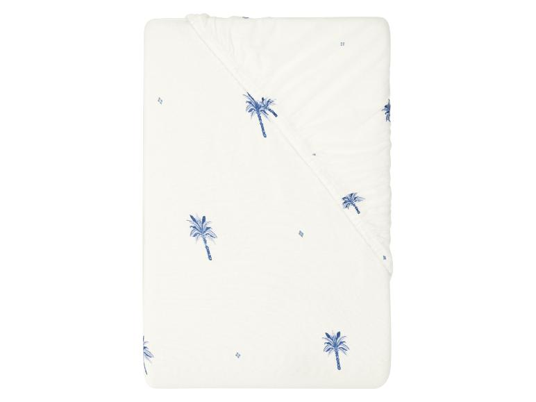Wit hoeslaken voor wieg met blauwe palmboomprint.