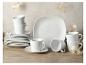 Wit servies met borden en kopjes op een houten tafel.