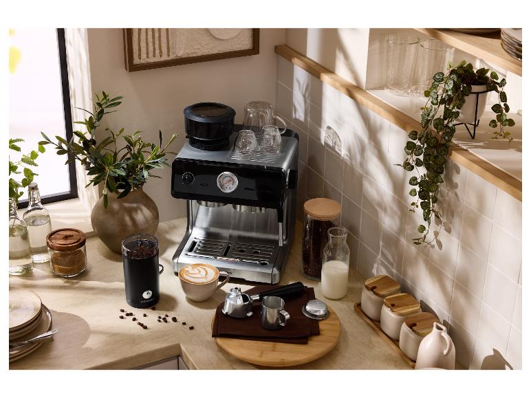 Keukenblad met espressomachine, koffiemolen, kopjes en koffiebonen.