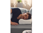 Man slaapt op zijn zij op grijs beddengoed, met zijn hoofd op een ergonomisch kussen.