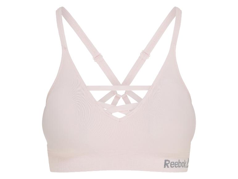 Lichtroze sportbeha met gekruiste bandjes en een tekstlogo.