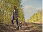 Vrouw in luipaardprint jas en hond in bijpassend vest op een bospad.
