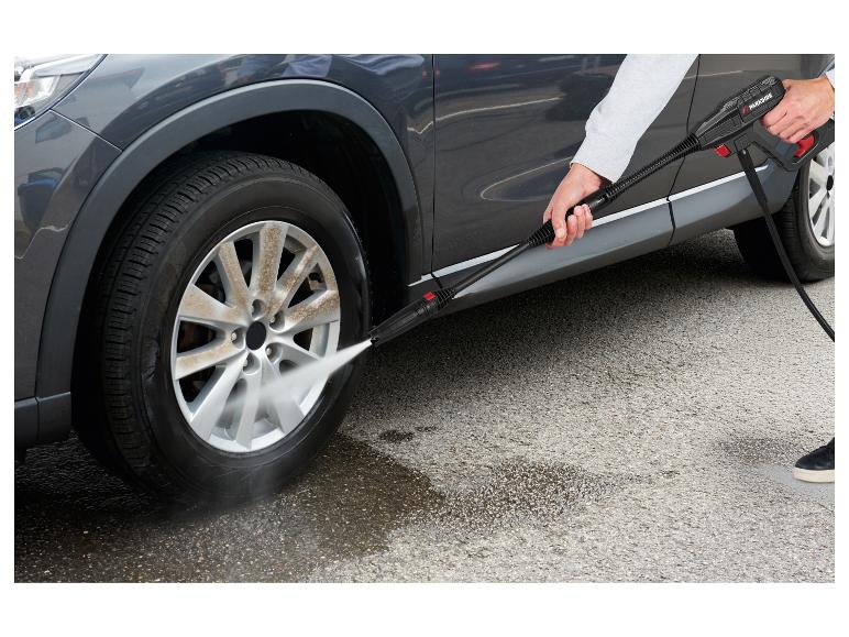 Persoon wast vuile autovelg met een hogedrukreiniger.