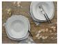 Twee sets witte borden met bestek op grijze servetten en een rustieke houten tafel.