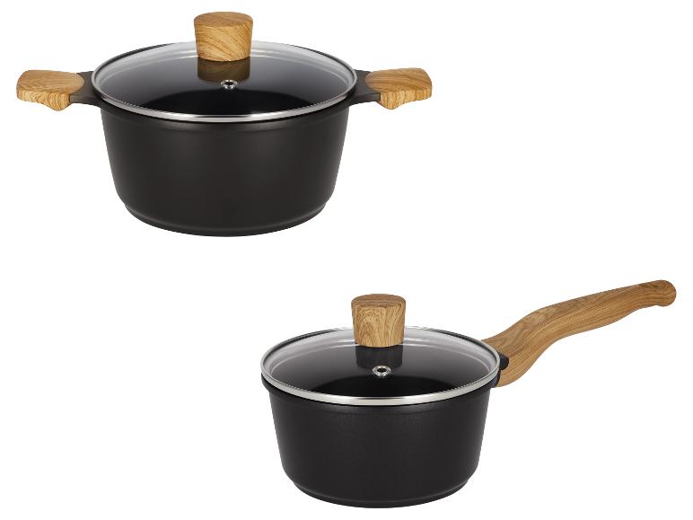 Twee zwarte pannen met houten handvatten en glazen deksels, één met twee korte handvatten, één met een lang handvat.