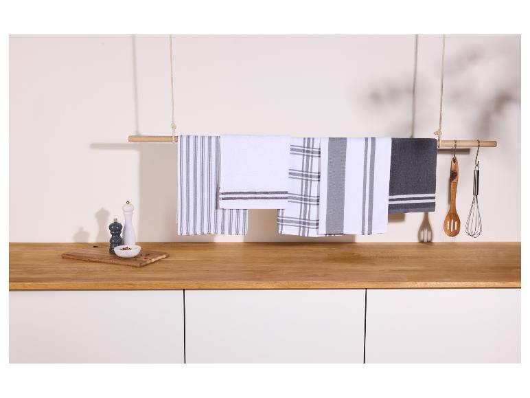 Katoenen theedoeken met strepen en ruiten, hangend boven een houten aanrecht met keukengerei.