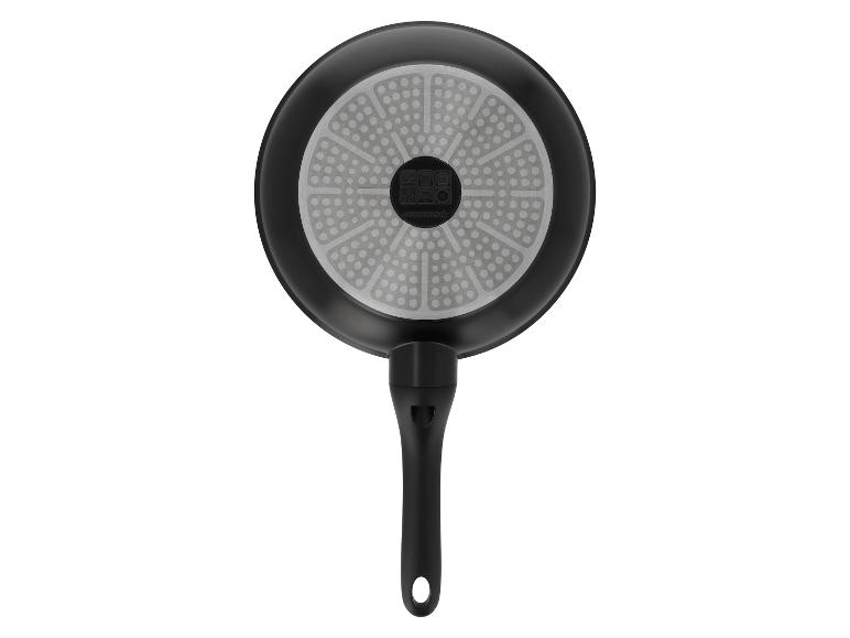 Onderkant van een zwarte koekenpan met handvat en een grijze gestippelde basis