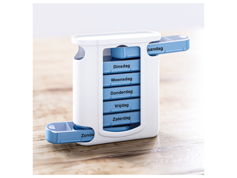 Een witte pillendoos met blauwe vakjes voor elke dag van de week.