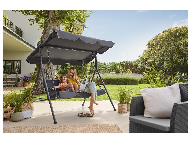 Moeder en kind schommelen op een tuinschommel met overkapping op een terras.