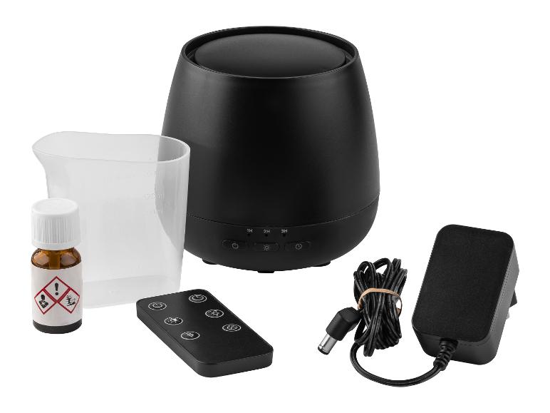 Zwarte aroma diffuser met afstandsbediening, maatbeker, etherische olie en stroomadapter.