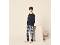 Jongen in donkerblauwe pyjama met lange mouwen met „Breakfast Club“-opdruk en geruite broek