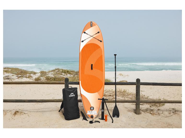 Oranje en wit SUP-board met accessoires op een zandstrand aan zee.