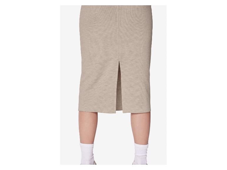 Beige midi rok met split aan de achterkant, gedragen door een persoon met witte sokken en sneakers.