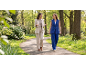 Twee vrouwen in stijlvolle pakken wandelen en praten in een groen park.