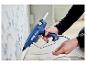 Persoon gebruikt een blauw Rapid PRO EG340 lijmpistool om een kabel langs een muur te bevestigen.