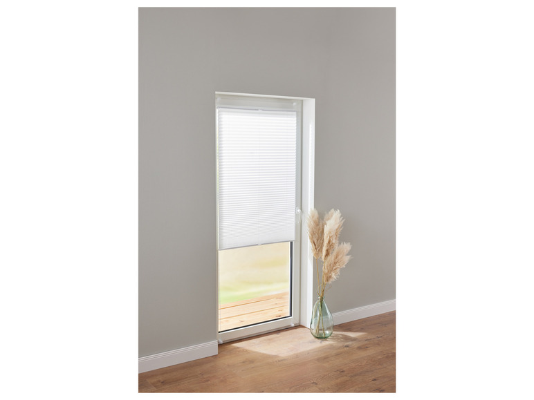 Witte plissé gordijn voor een deur met houten vloer