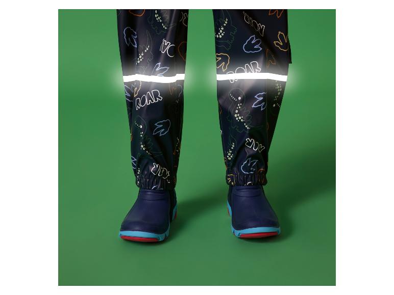 Kinderwaterdichte broek met dinoprint en reflecterende strepen, gecombineerd met blauwe laarzen.