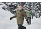 Jongen in een groene pufferjas en man in een groene outdoorjas rennen in de sneeuw.