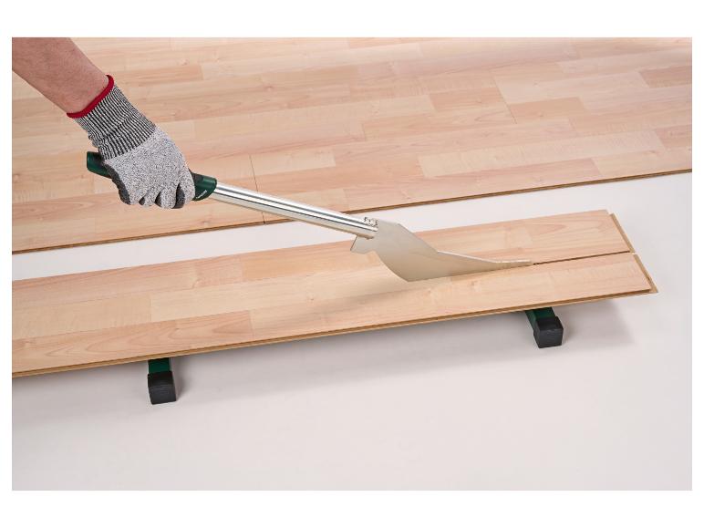 Een arbeider snijdt een laminaatplank met een laminaatsnijder.