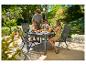 Familie geniet van ontbijt aan een tuintafel en stoelen buiten.