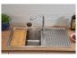 Keukenspoelbak met houten snijplank, kraan en afdruiprek op een houten aanrechtblad.