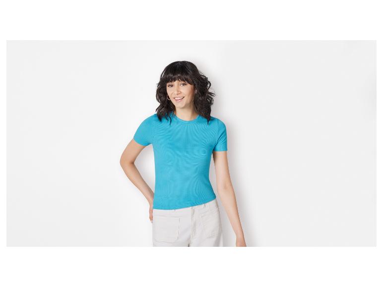 Vrouw in lichtblauw shirt en witte broek.