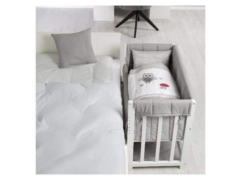 Witte babywieg met uilenbeddengoed en een eenpersoonsbed met een grijs kussen.