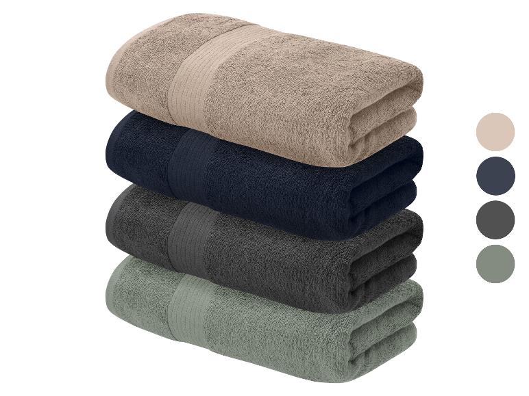 Een stapel van vier gevouwen handdoeken in neutrale kleuren, met kleurstalen aan de zijkant.