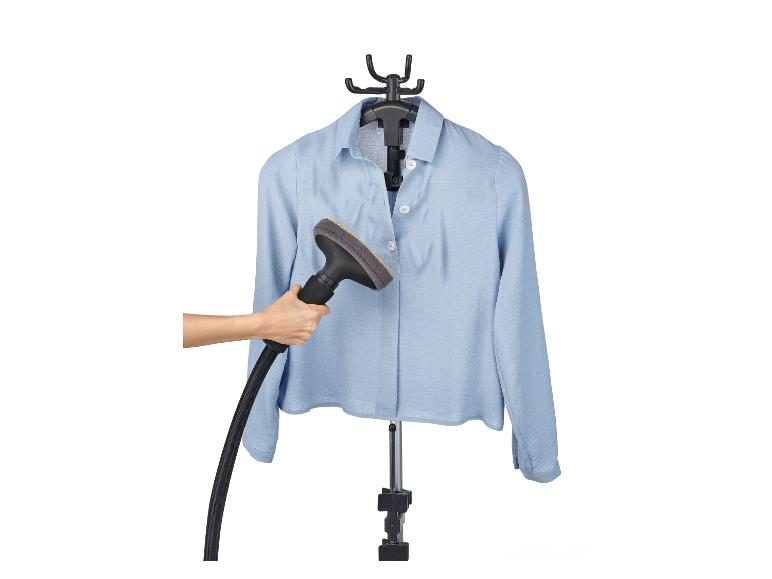 Een vrouw strijkt een lichtblauw overhemd met een handstomer.