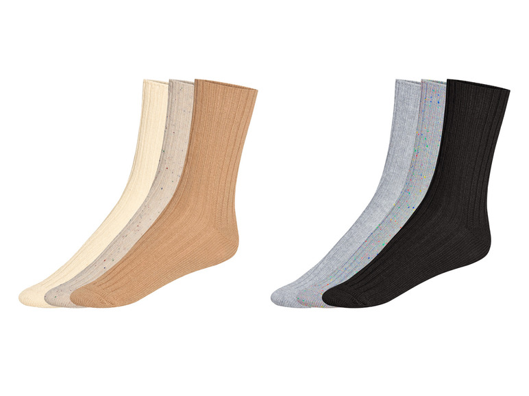 Drie paar sokken in beige, grijs en zwart met kleurrijke stippen.