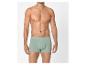 Man in lichtgroene boxershort, staand tegen een witte achtergrond.