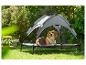 Hond op een verhoogd bed met luifel in een tuin.