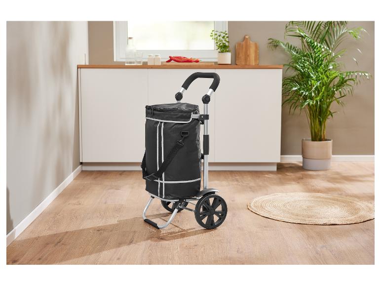 Zwarte boodschappentrolley met wielen in een moderne keuken met planten.
